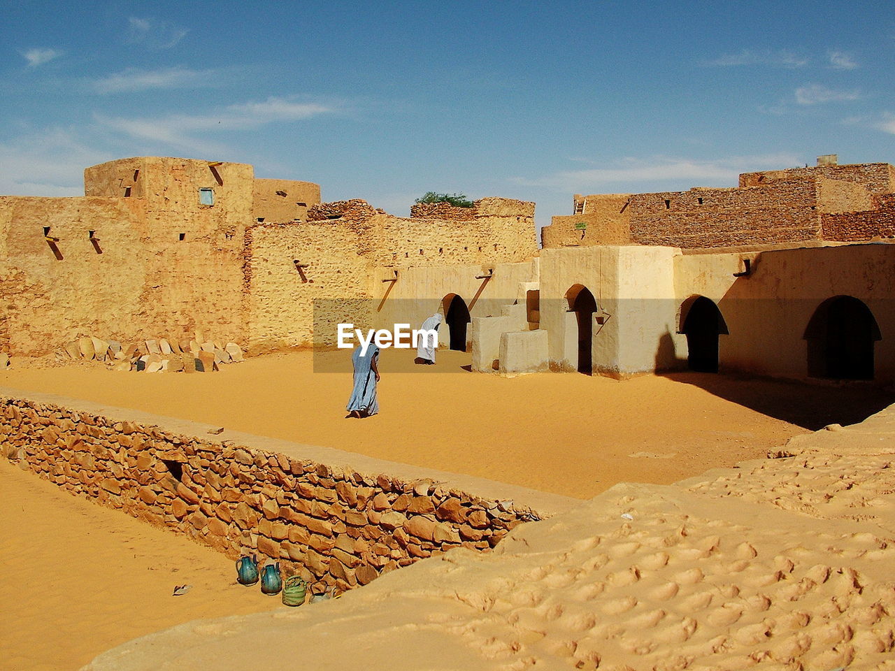 REAR VIEW OF PEOPLE WALKING ON SAND AGAINST SKY