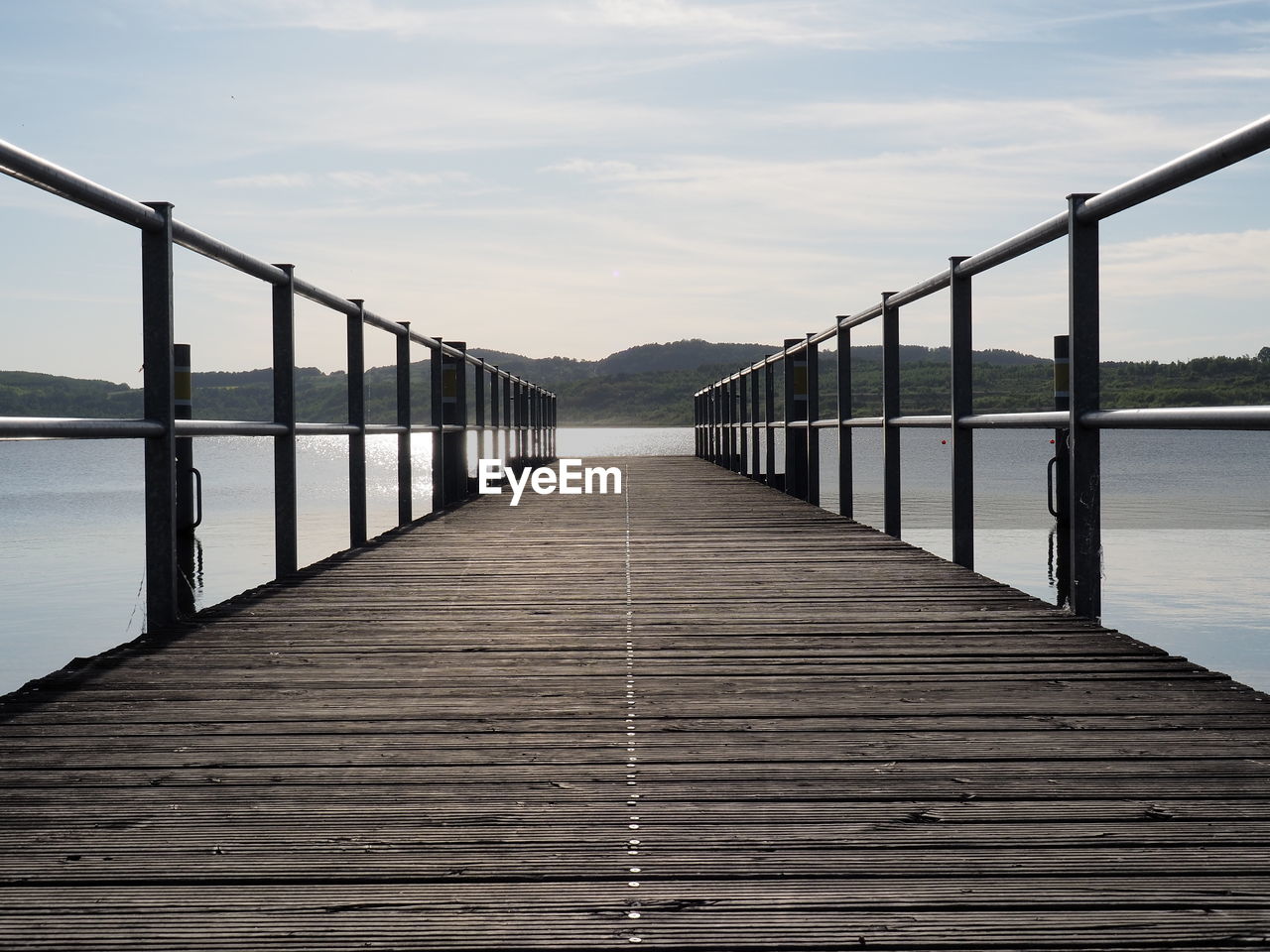 Footbridge over lake against sky