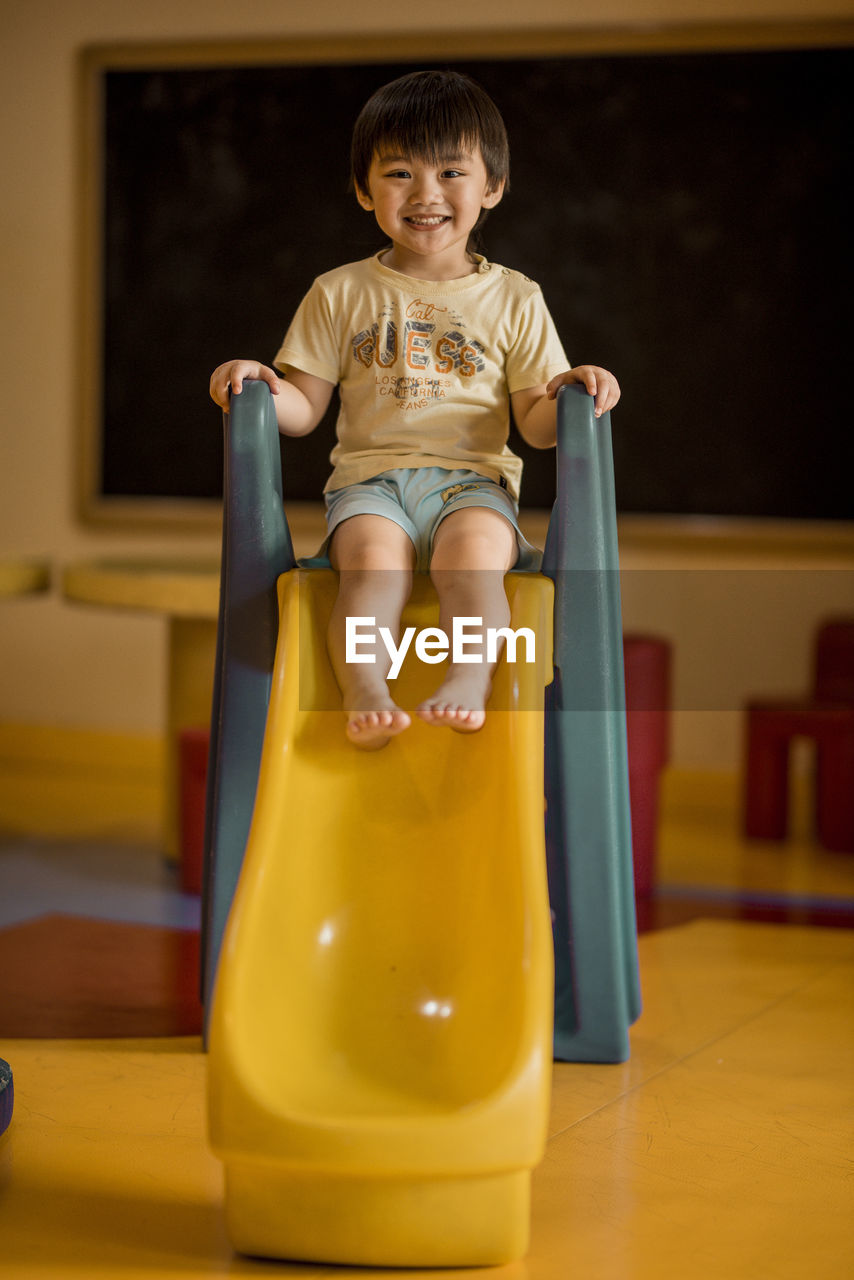 Portrait of smiling boy sitting on slide