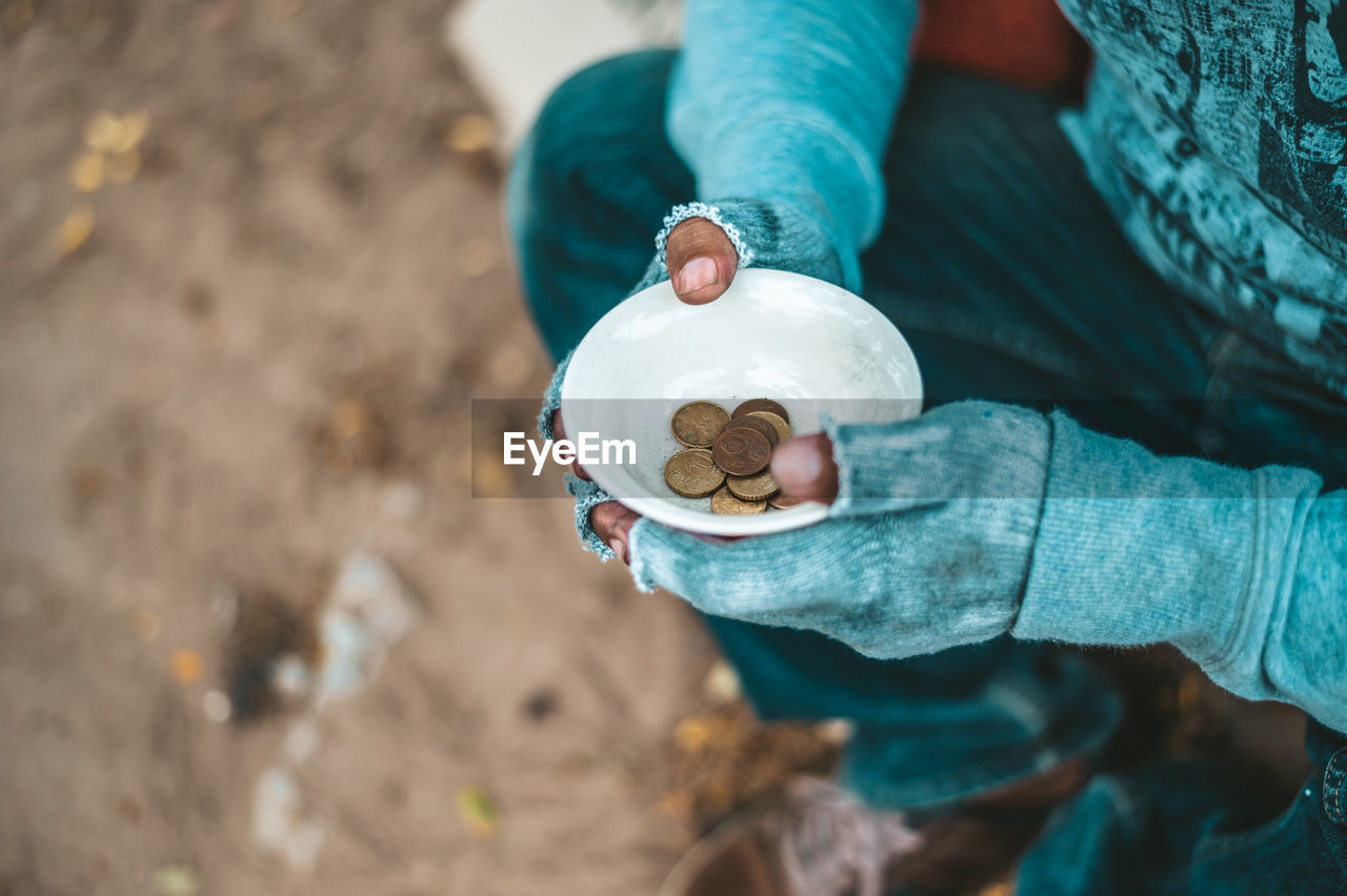 High angle view of beggar with coins in bowl