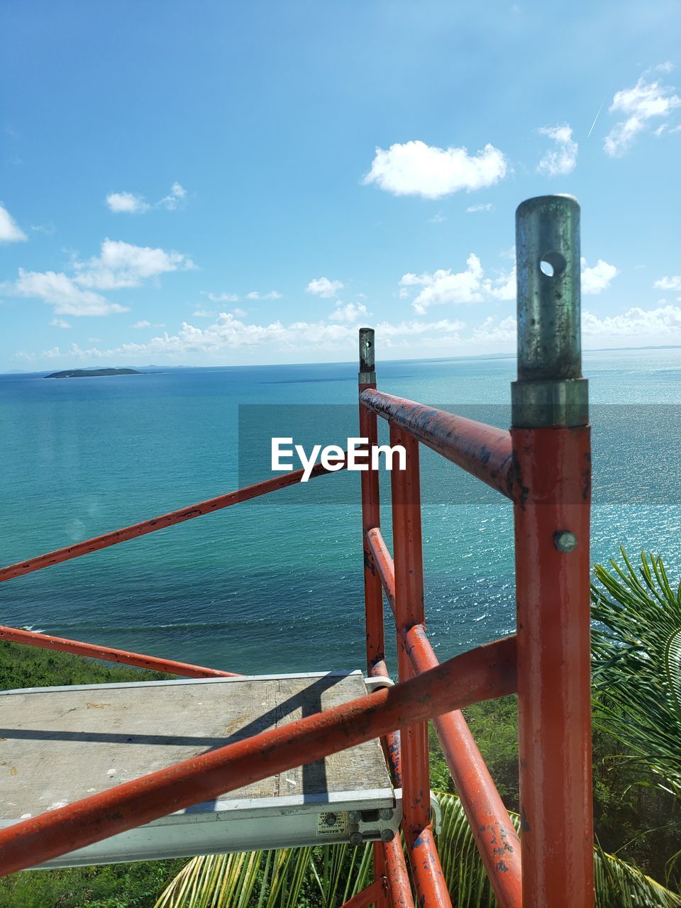 WOODEN RAILING BY SEA AGAINST SKY