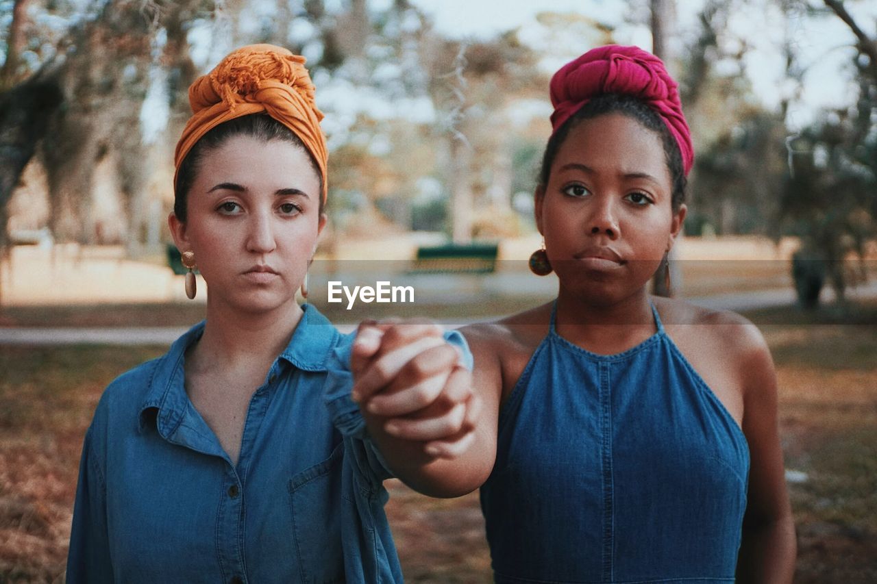 Portrait of young women holding hands while standing at park