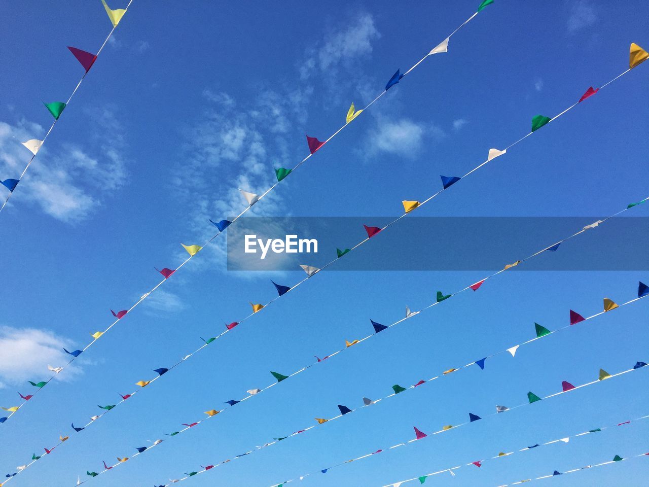 Low angle view of multi colored buntings hanging against blue sky