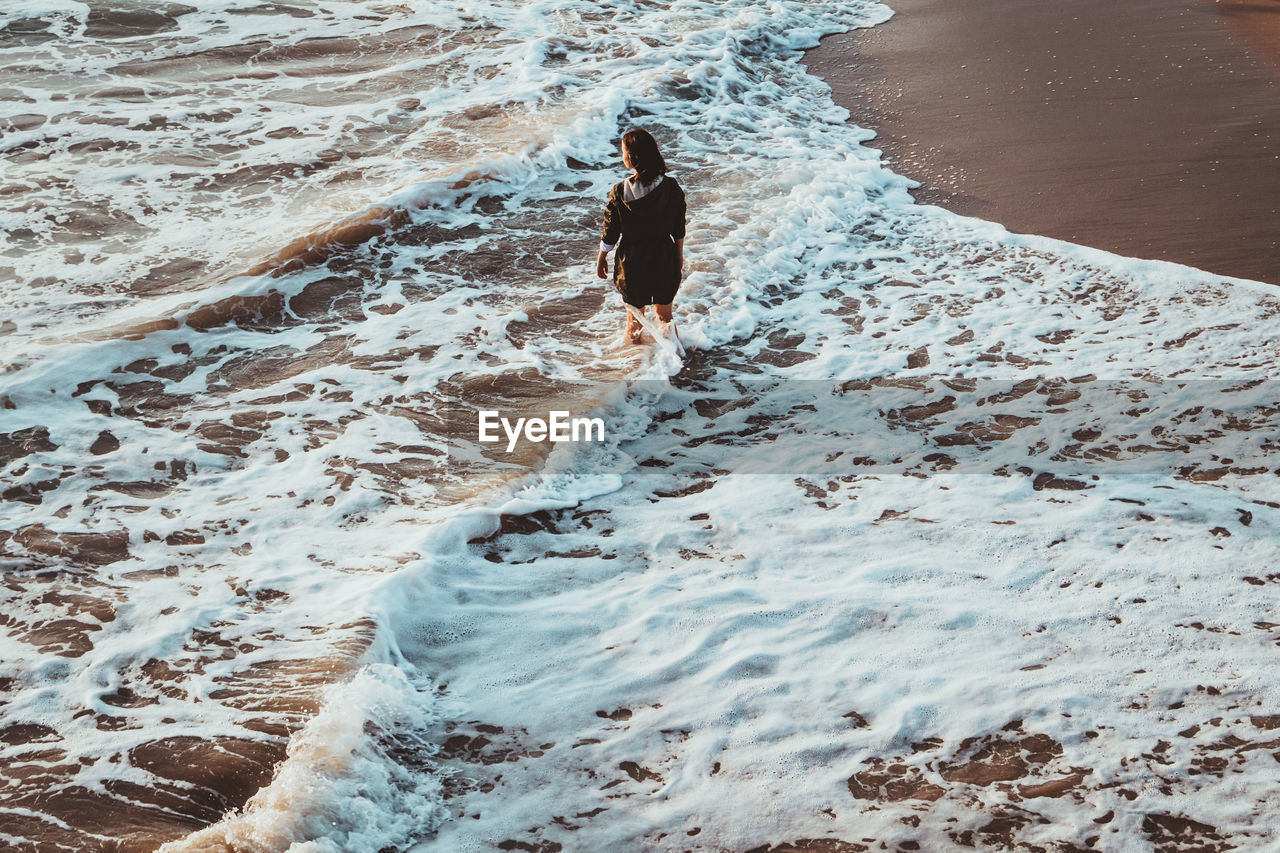 Full length of woman standing on shore at beach