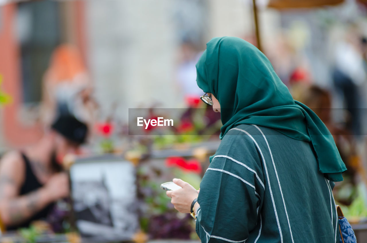 adult, city, focus on foreground, lifestyles, person, men, clothing, one person, spring, architecture, hood, outdoors, day, hood - clothing, street, women, waist up, side view, technology