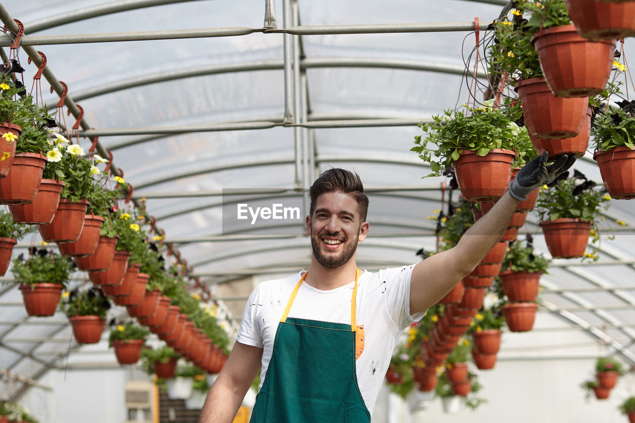 Portrait of smiling young man standing in greenhouse