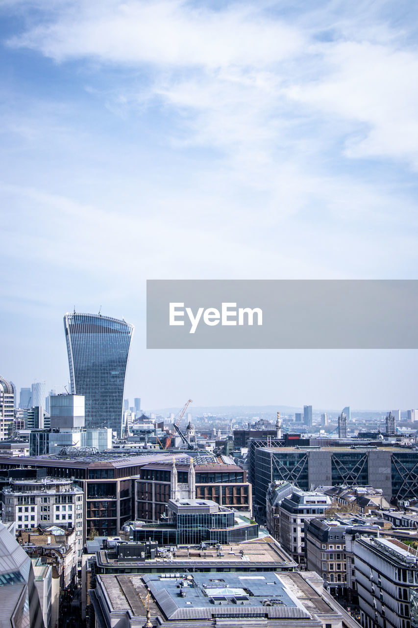 HIGH ANGLE VIEW OF BUILDINGS BY CITY AGAINST SKY