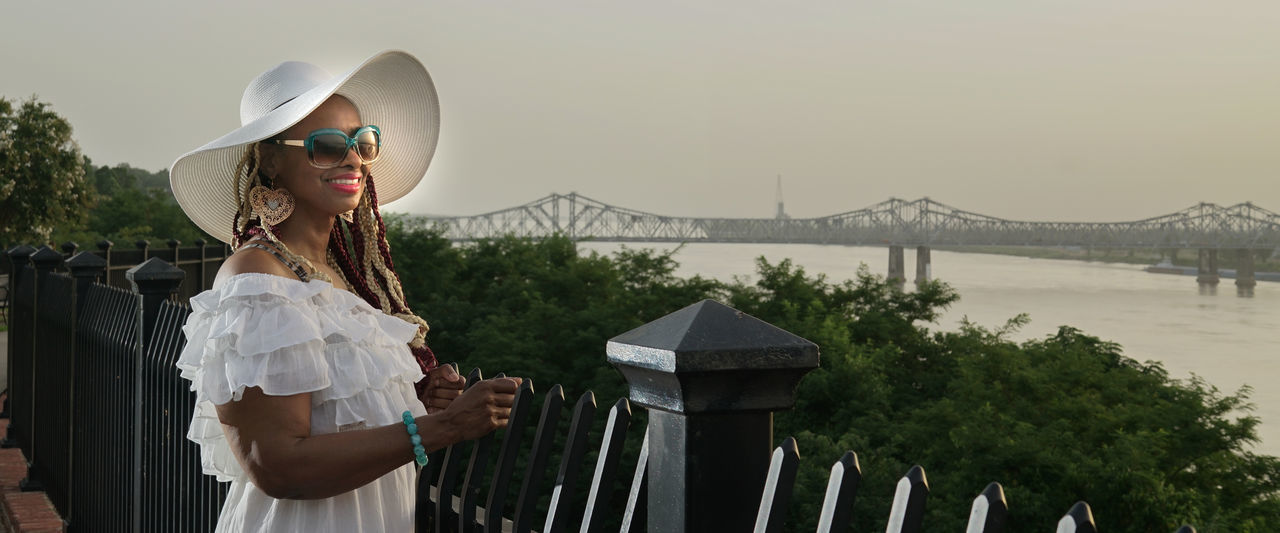 WOMAN STANDING BY RAILING AGAINST BRIDGE