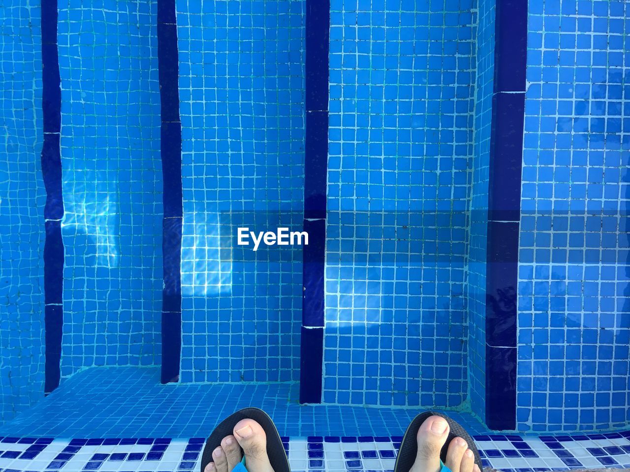 Low section of man standing by swimming pool