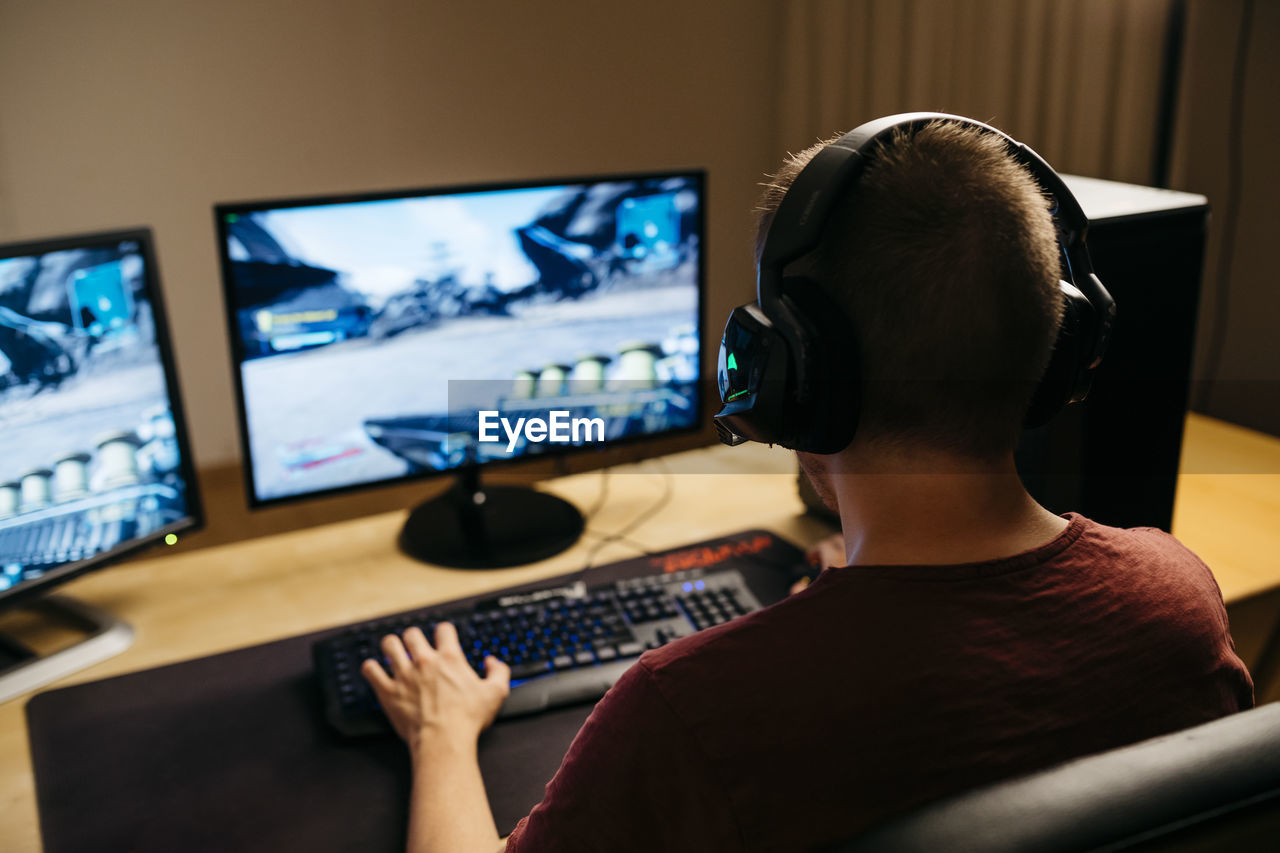 Young man playing video games with computer at desk