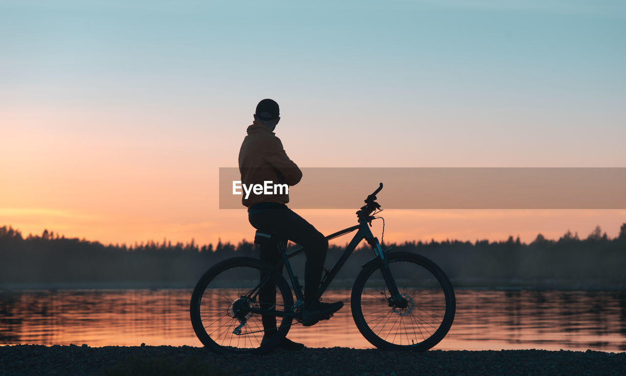 Cyclist enjoys the sunset near the forest lake