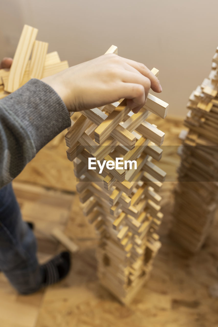 Low section of man building tower of wooden blocks at home