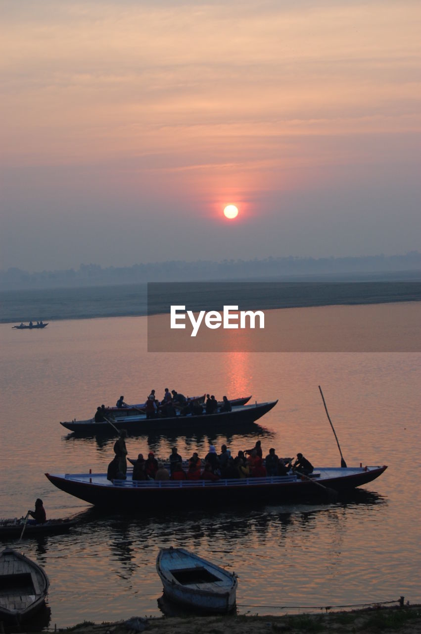 SHIP MOORED IN SEA AGAINST SKY DURING SUNSET