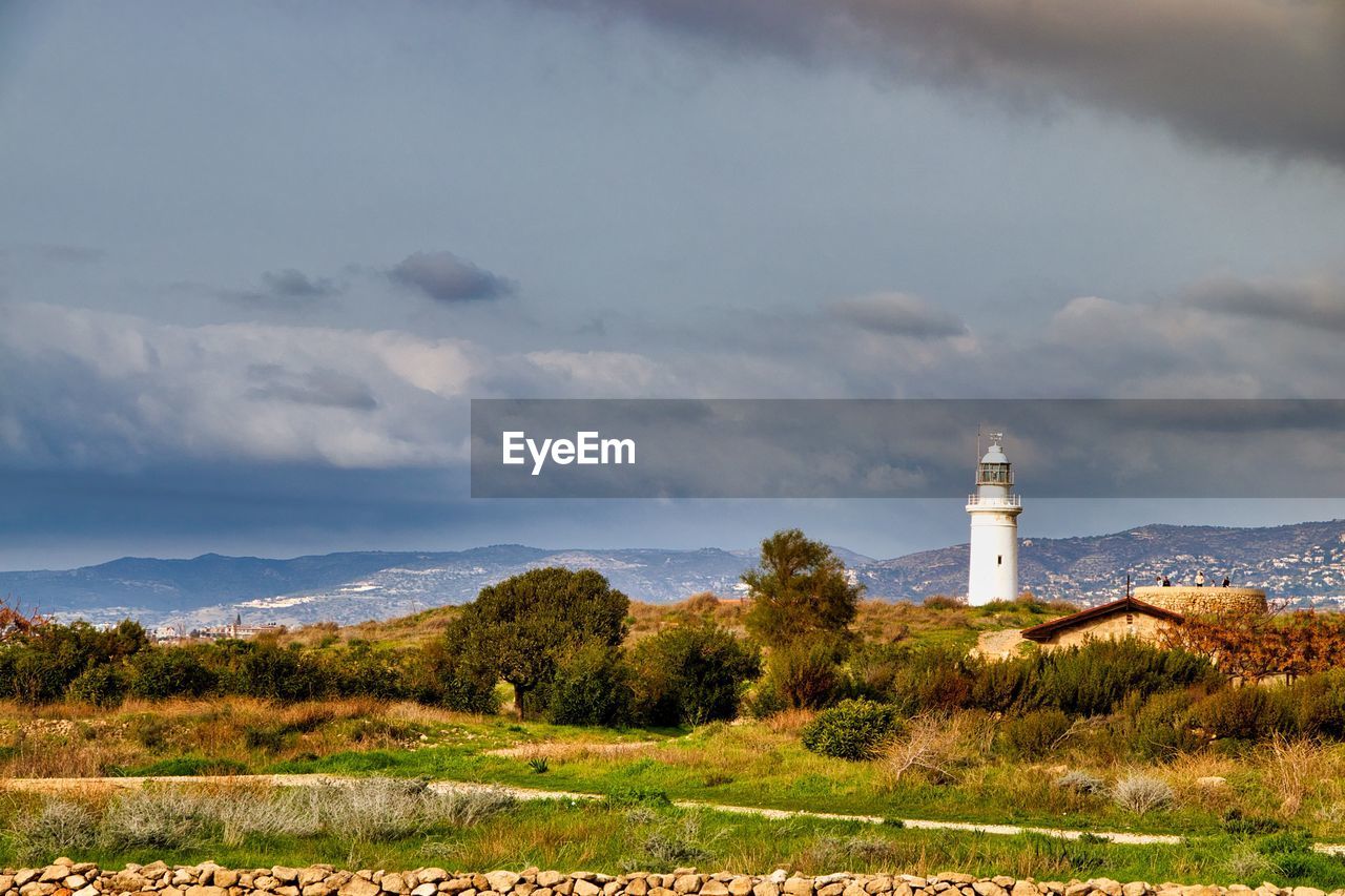 Lighthouse by building against sky