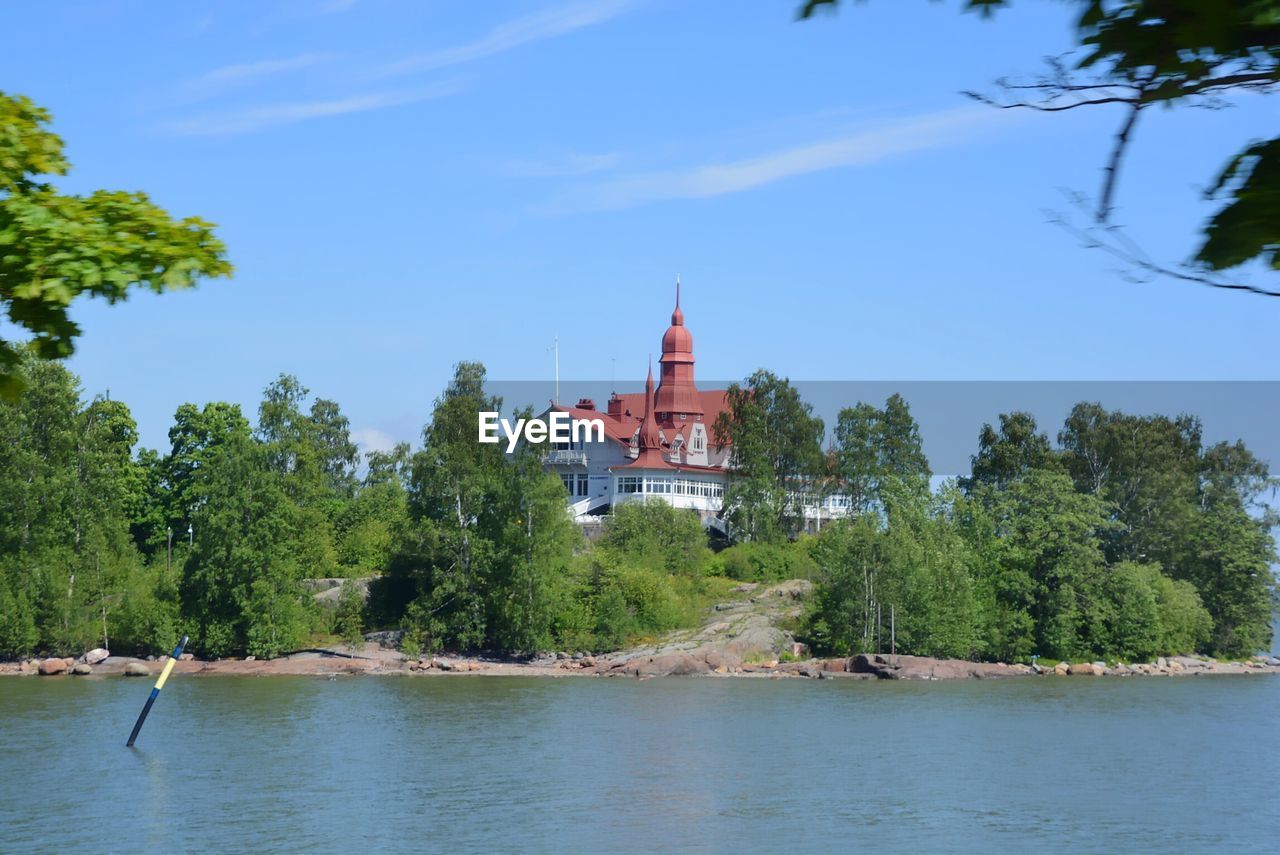 Scenic view of river by building against sky