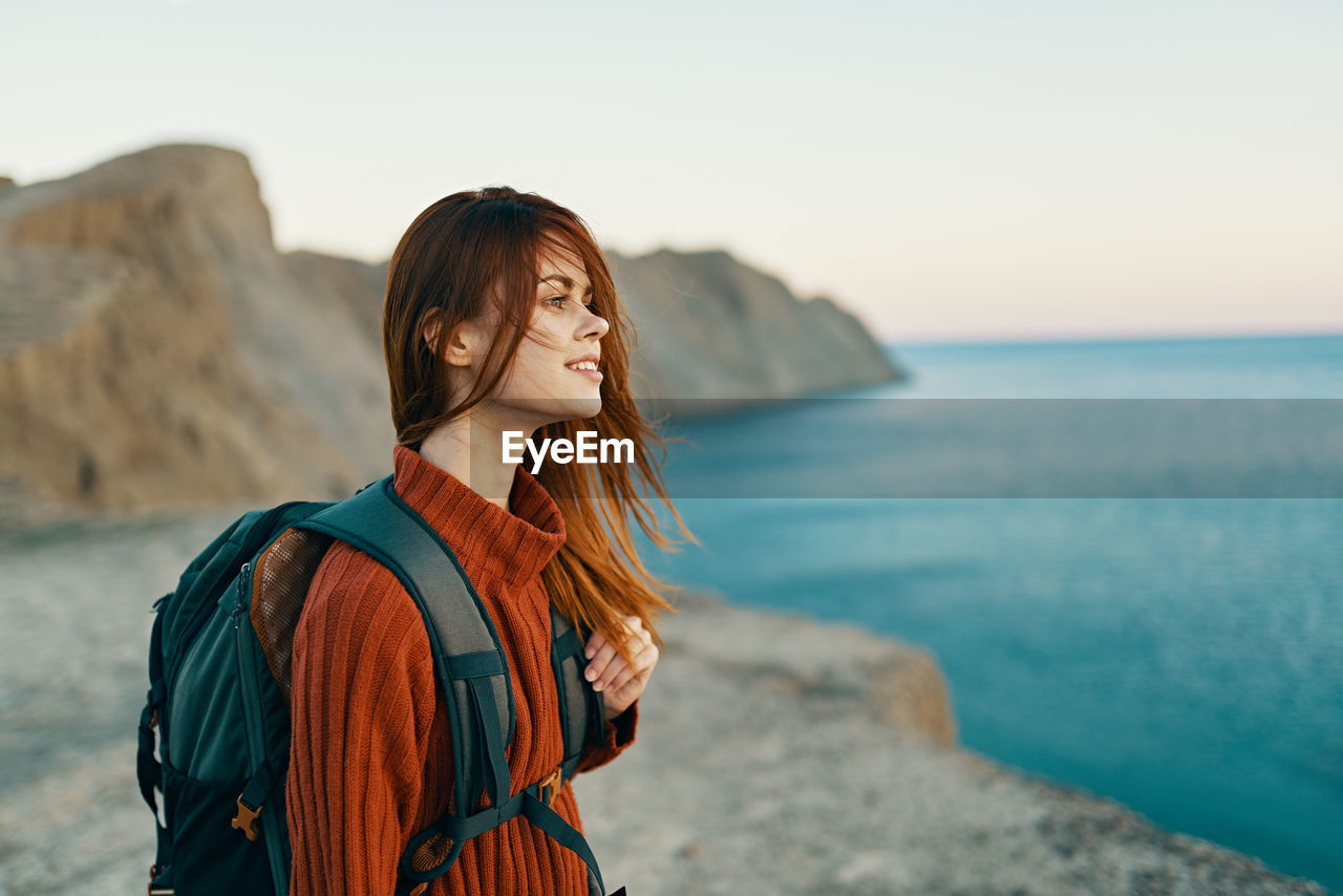 Young woman looking at sea against sky