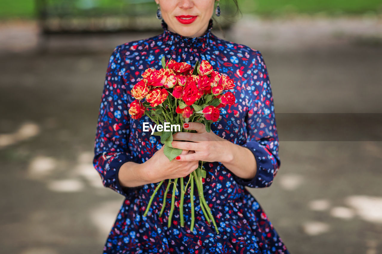 Elegant unrecognizable woman holding a bunch of red roses