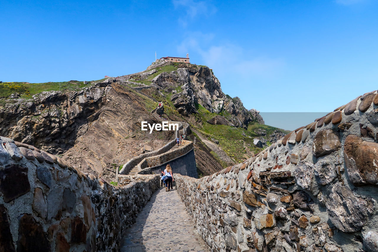 Rear view of people walking on fortified wall