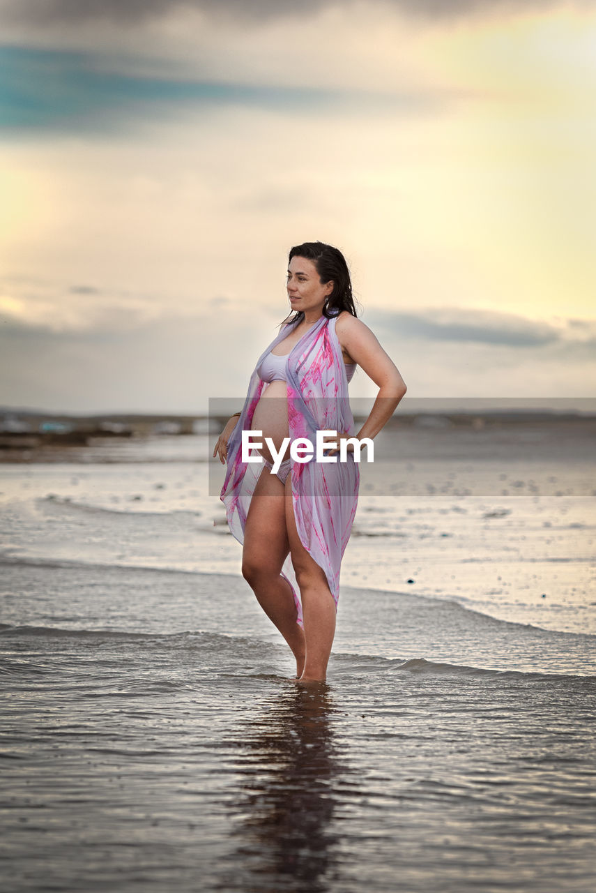 Full length of woman standing at beach against sky