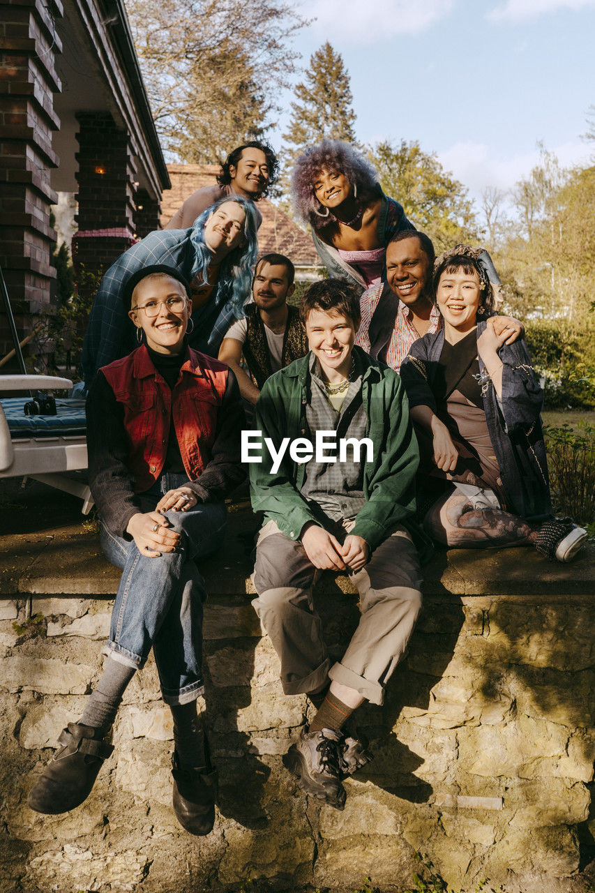 Portrait of happy friends from lgbtq community sitting on porch at sunny day