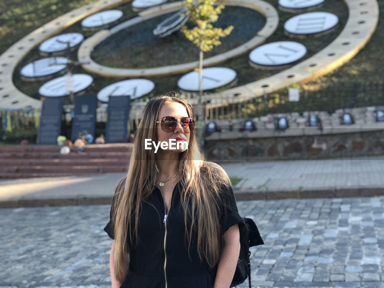 Portrait of young woman wearing sunglasses while standing against wall