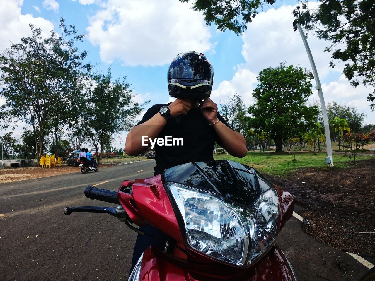 Man wearing helmet while sitting on motorcycle against trees