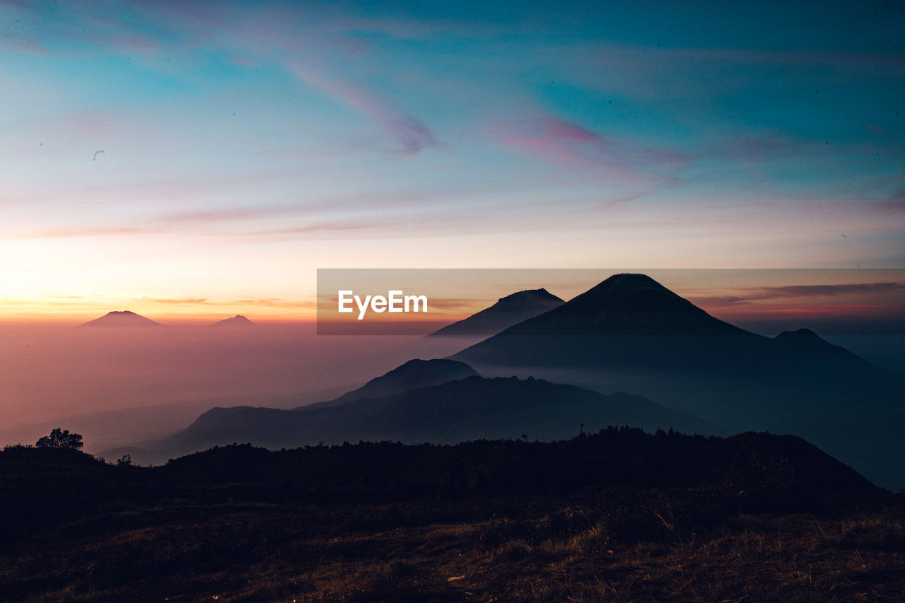 SCENIC VIEW OF SILHOUETTE MOUNTAINS AGAINST SKY AT SUNSET