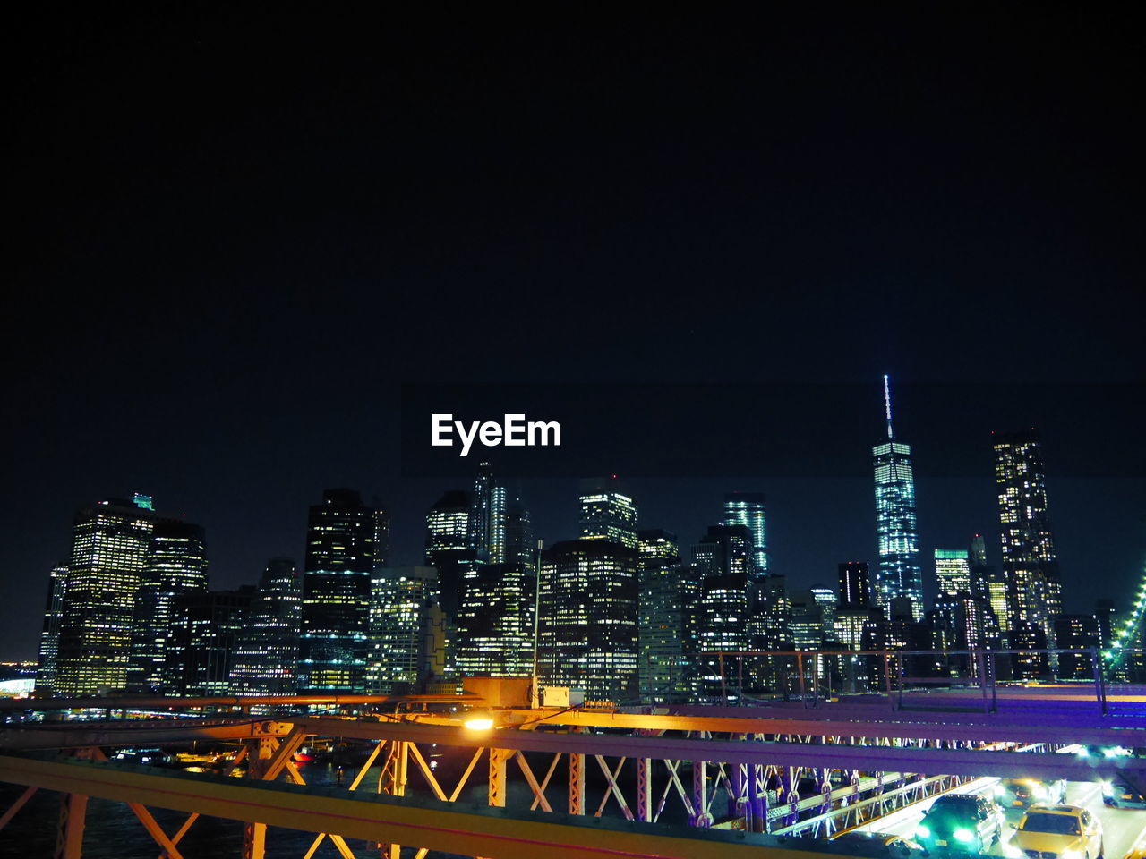 Illuminated city skyscrapers against sky seen from brooklyn bridge