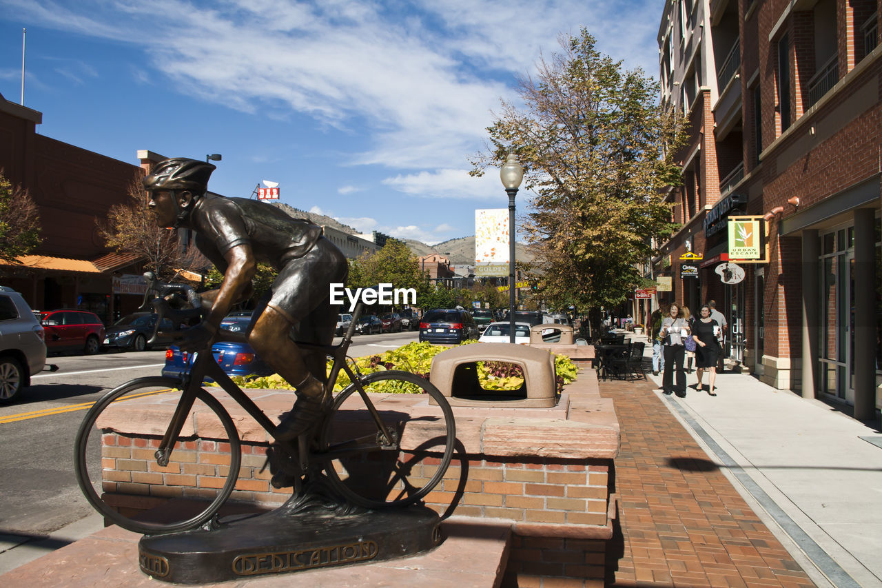 Bronze statue of bicyclist on footpath in city