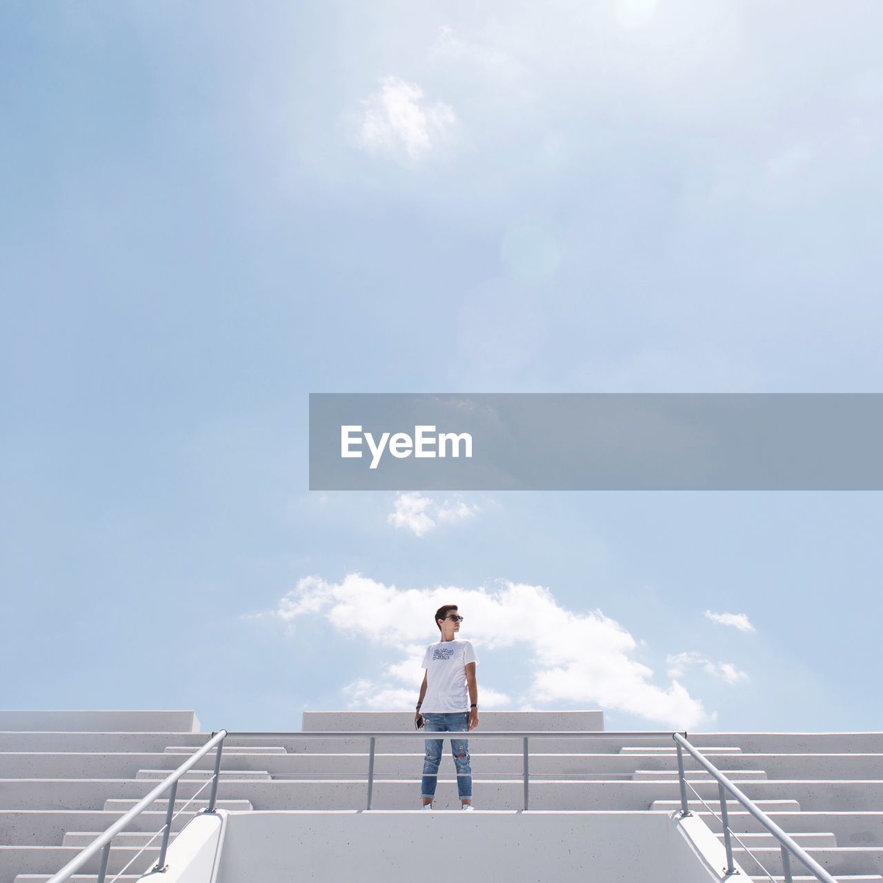 Low angle view of young man standing on steps against sky
