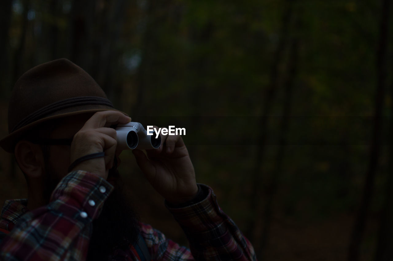 Close-up of man looking through binoculars in forest