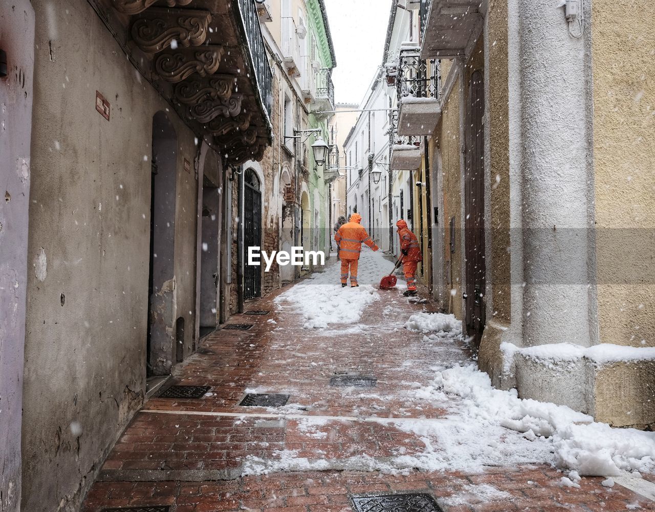 People cleaning snow in alley during winter