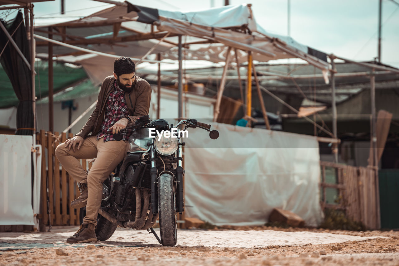 Young man standing by motorcycle