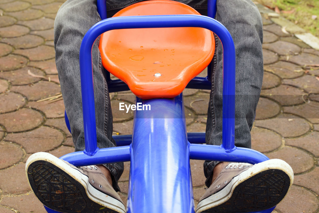 Low section of man sitting on seesaw at playground