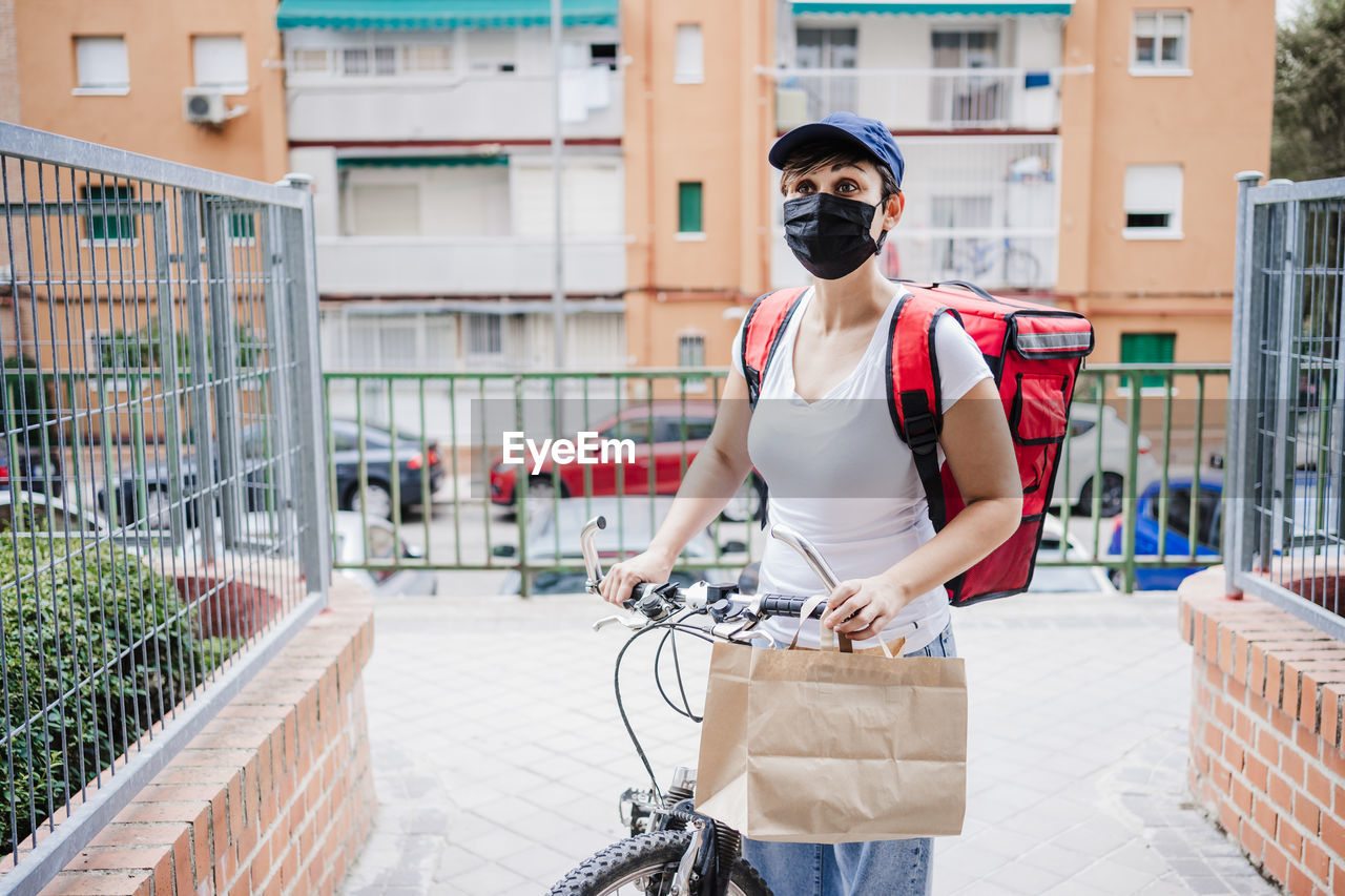 Delivery person wearing mask standing against building