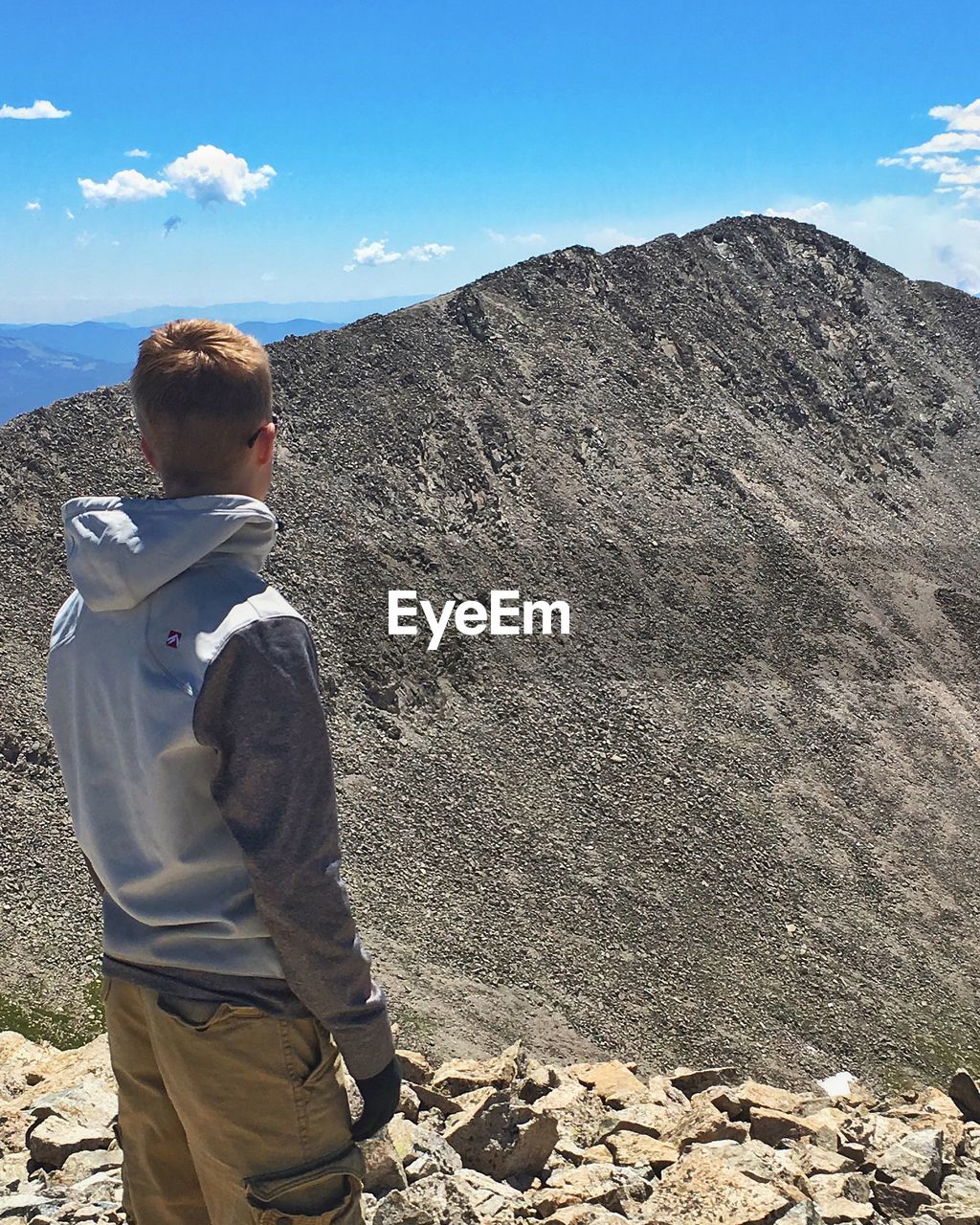 BOY STANDING ON LANDSCAPE AGAINST SKY