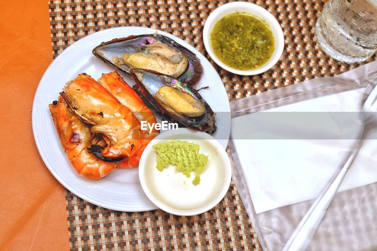 food and drink, food, healthy eating, freshness, seafood, plate, wellbeing, table, meal, high angle view, no people, dish, eating utensil, kitchen utensil, fish, vegetable, fruit, shellfish, drink, indoors, dinner, household equipment, bowl, produce, citrus fruit, directly above, place setting, animal, glass, cuisine, crockery, meat, fork, refreshment, restaurant, barbecue, drinking glass, serving size, still life, asian food, lemon, grilled, sauce, close-up, savory food, tablecloth, gourmet