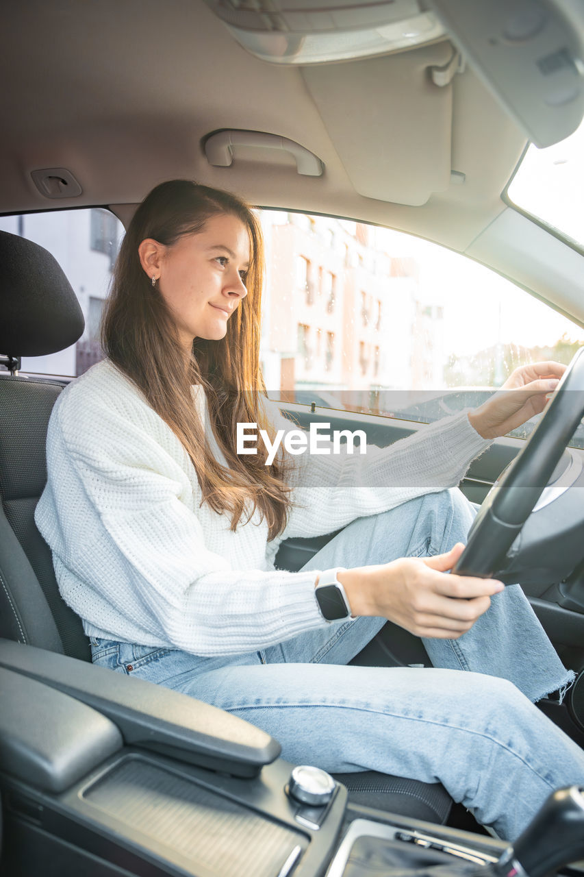 portrait of young woman using phone while sitting in car