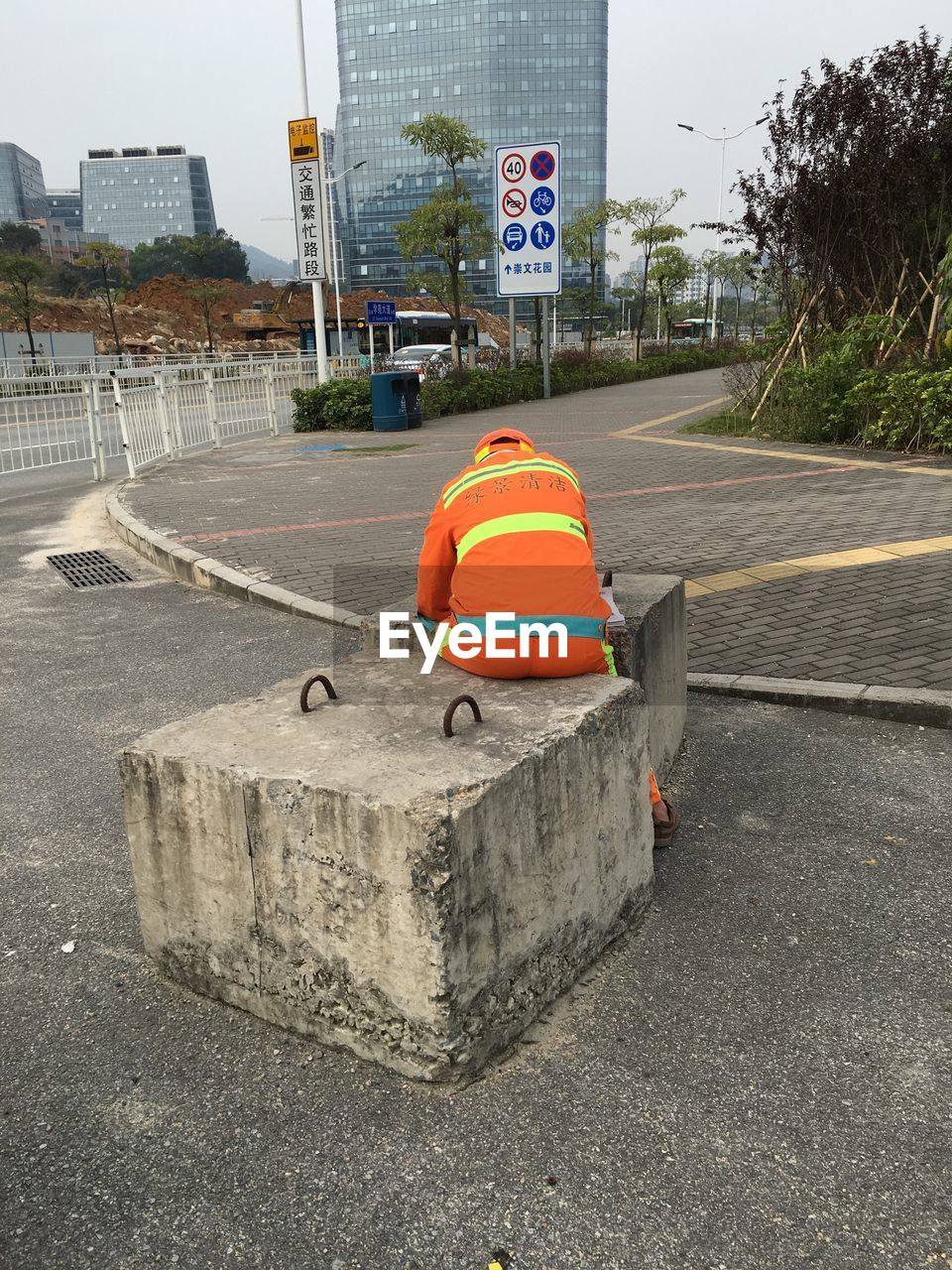 Rear view of street cleaner sitting on stone structure