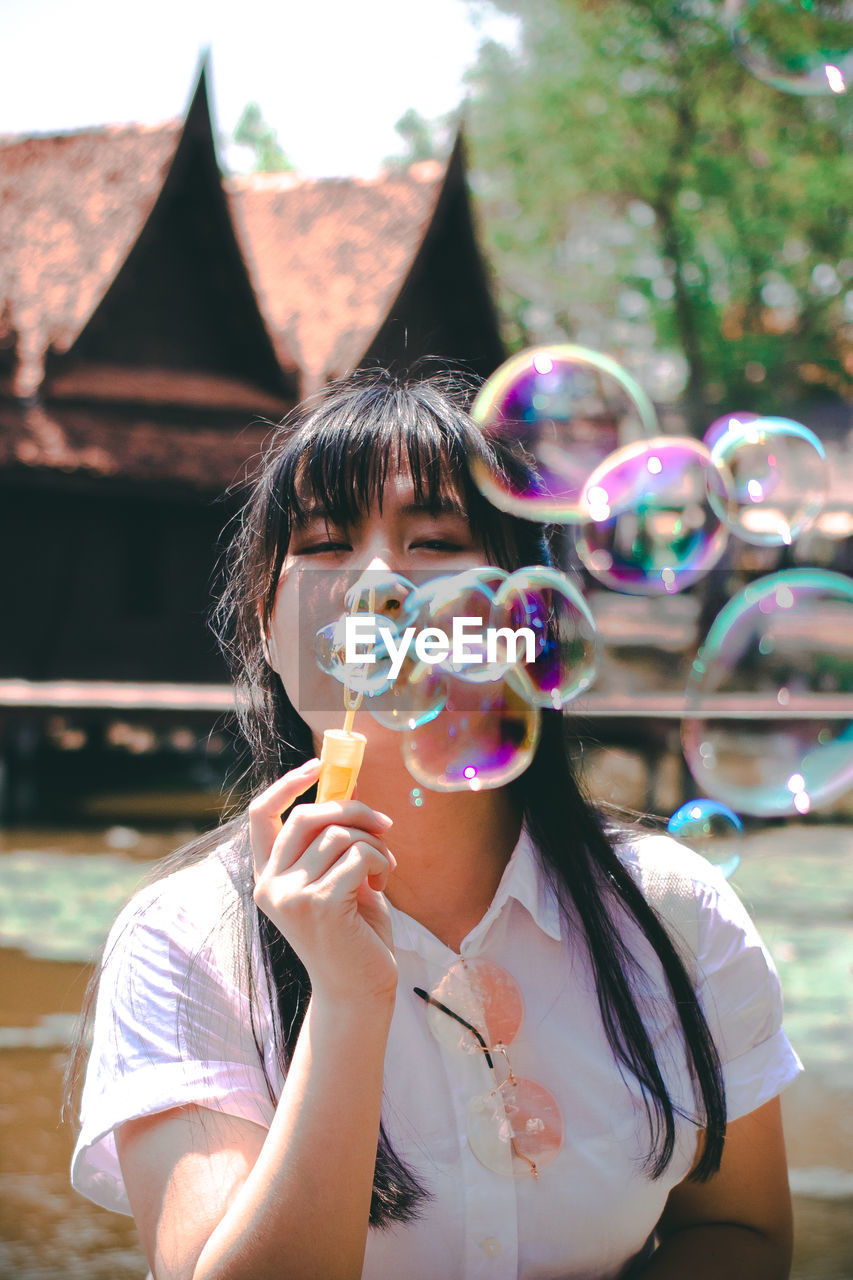 Portrait of woman blowing bubbles outdoors