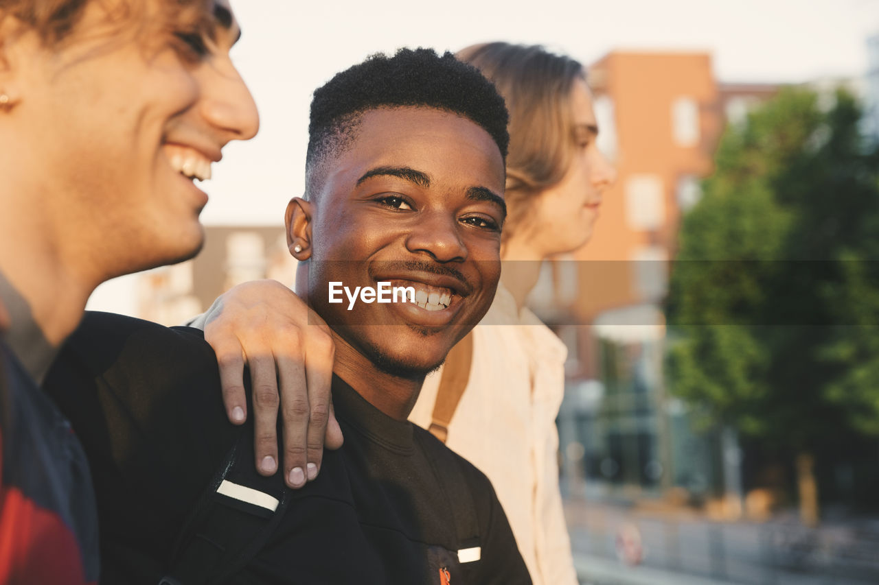 Portrait of smiling young man with friends standing in city