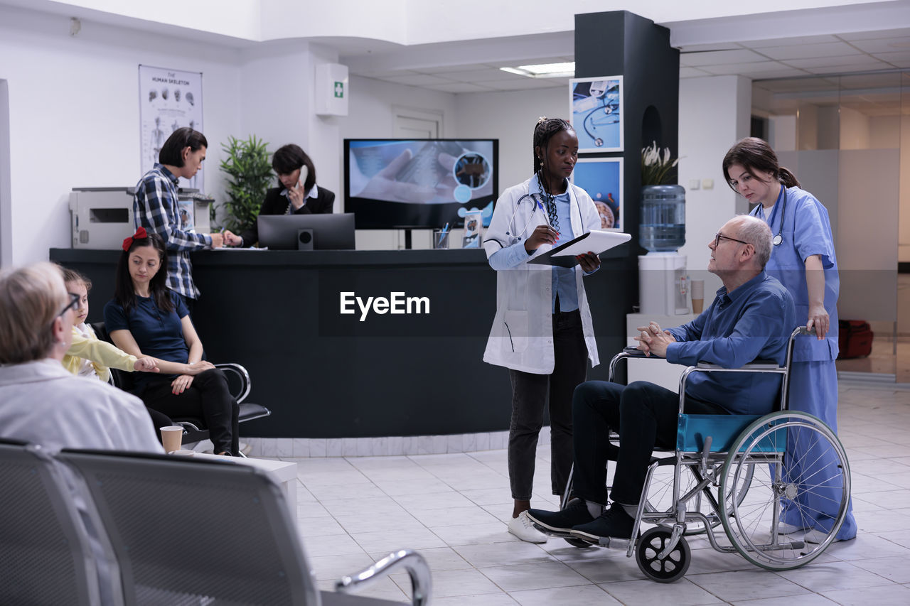 Doctor consulting with patient on wheelchair in hospital