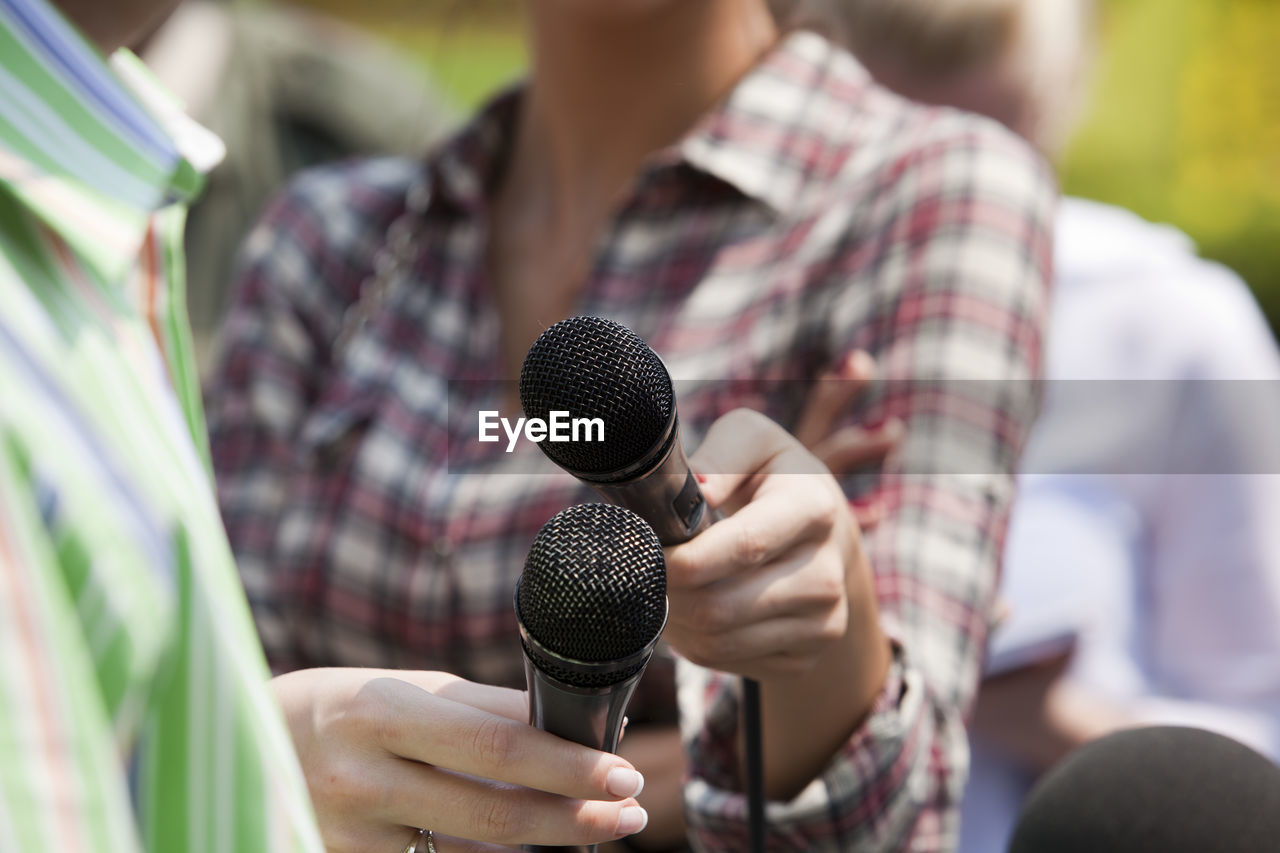 Midsection of female journalist interviewing man on street