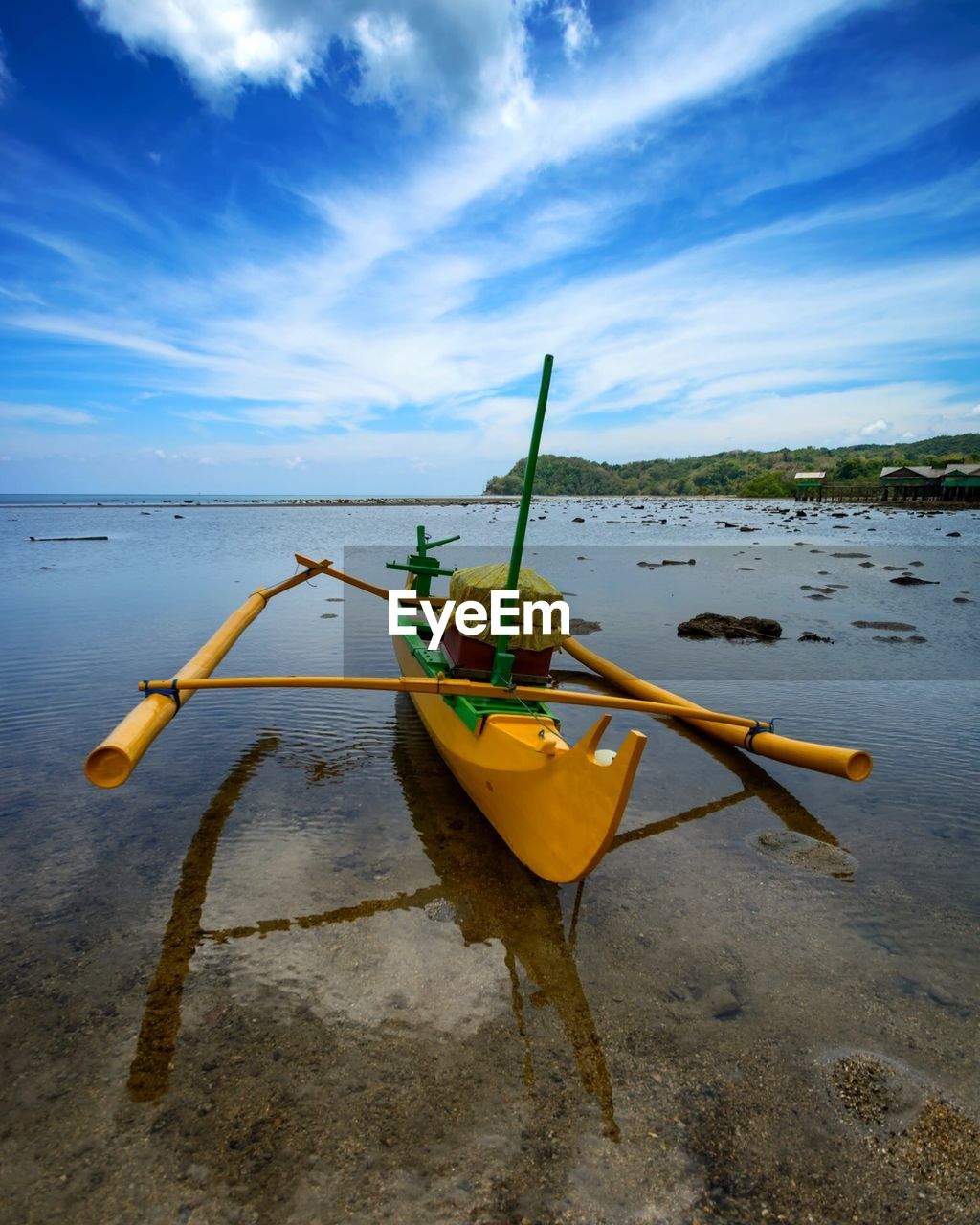 Yellow boat moored at beach against sky