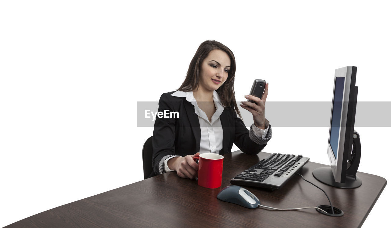 YOUNG WOMAN USING SMART PHONE AND COFFEE CUP