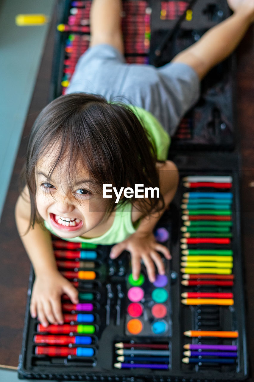 High angle view portrait of angry girl on art and craft equipment