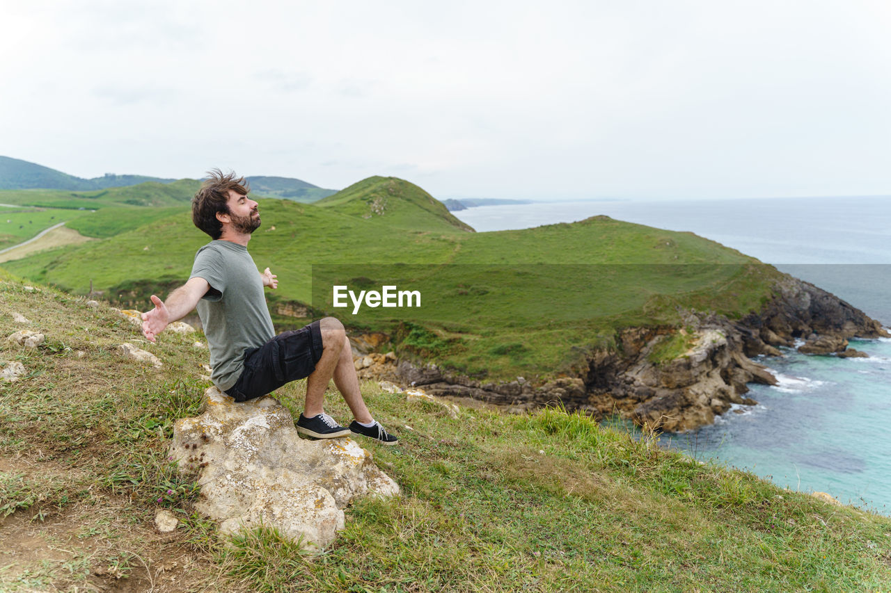 Rear view of man standing on mountain against sky