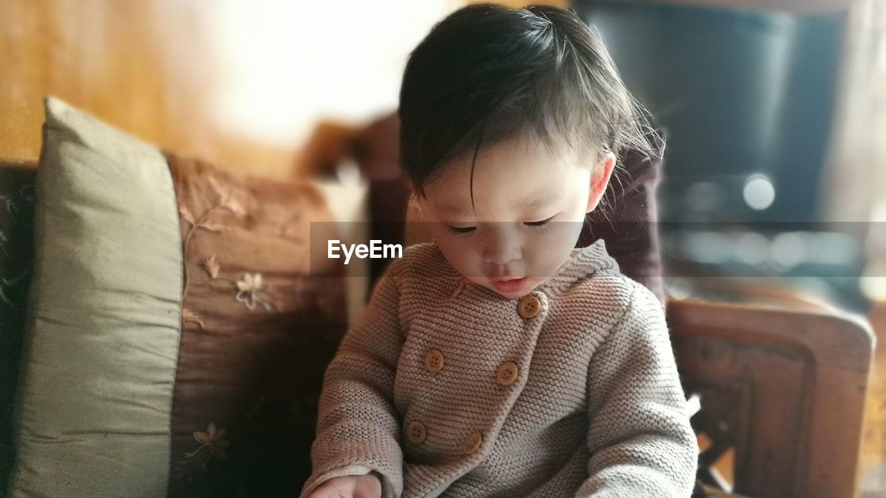Cute toddler sitting on sofa at home