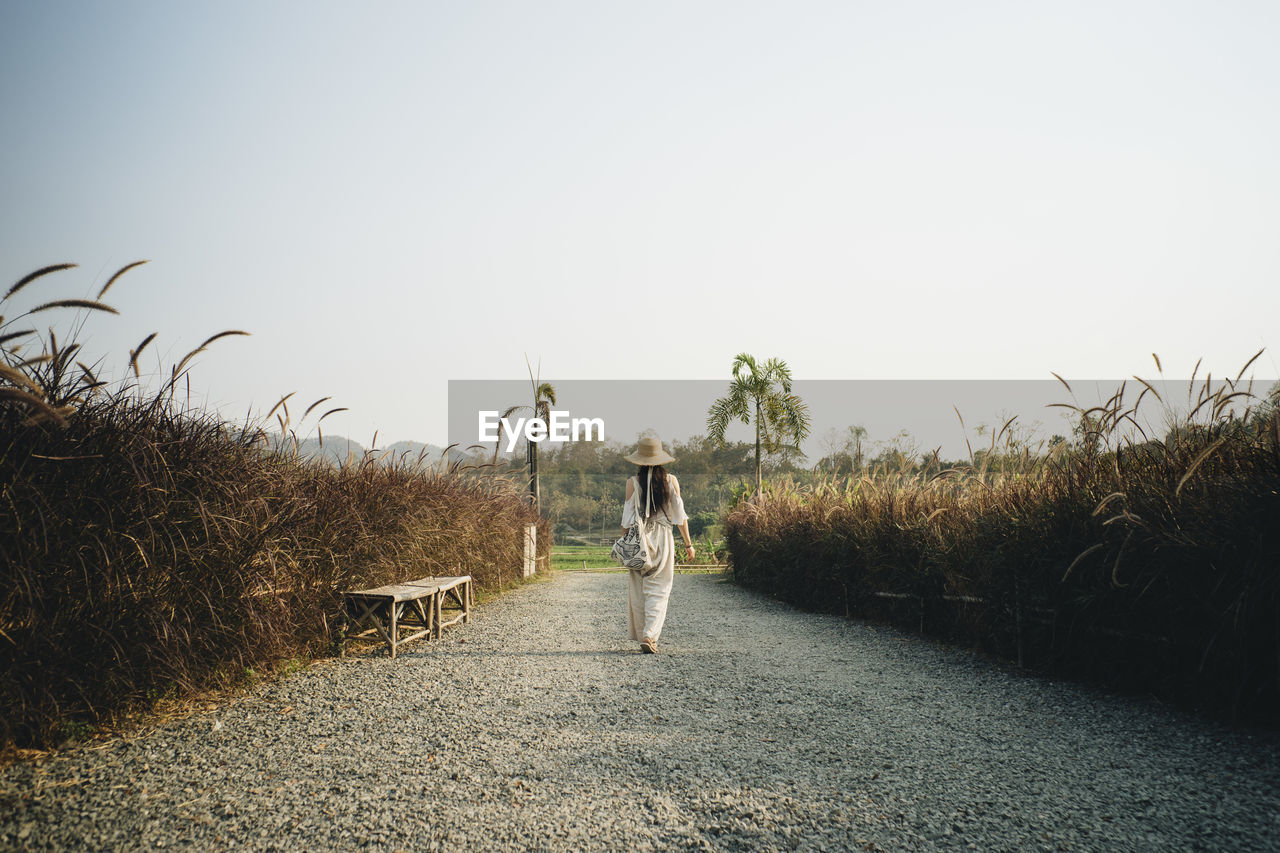 Rear view of woman walking on footpath against sky