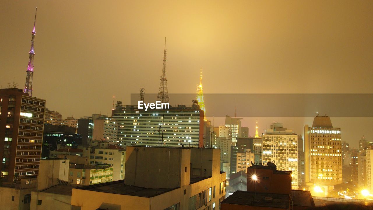 Illuminated buildings in city against sky at night